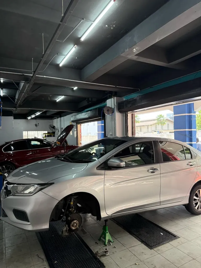Silver sedan raised on axle stands with a front wheel removed and the brake assembly exposed