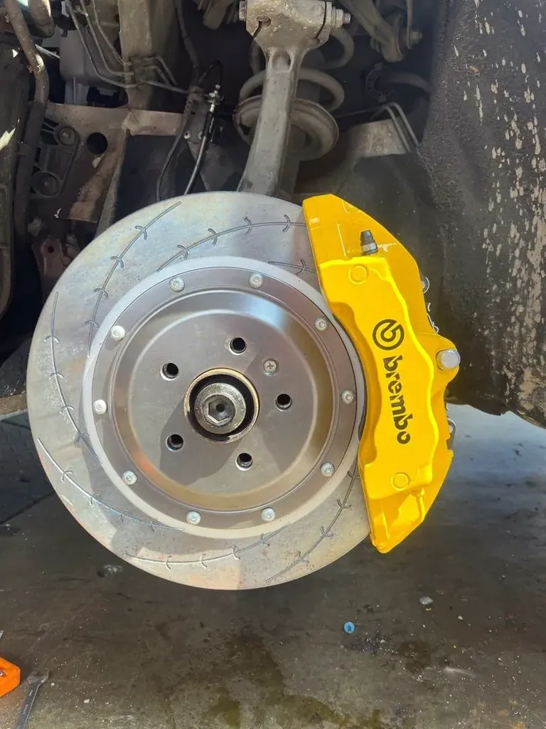 Yellow Brembo brake caliper and drilled disc on a wheel hub with the wheel removed