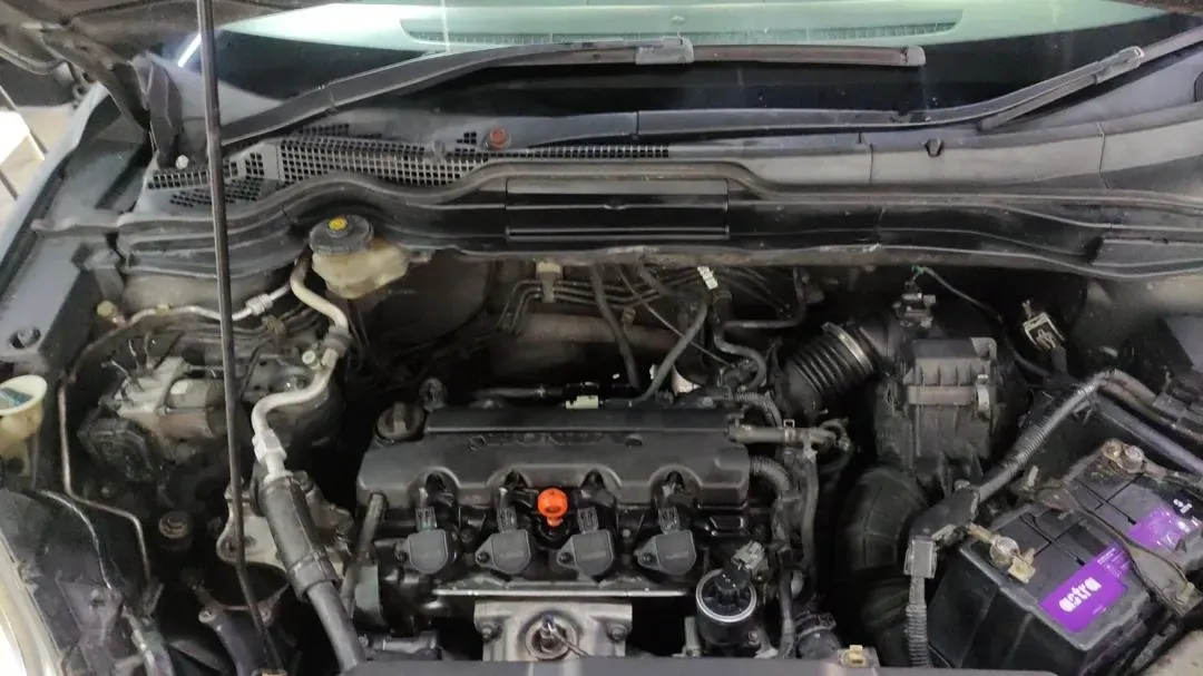 Honda engine bay with the bonnet open at Otoka Garage, showing the orange oil filler cap and the battery